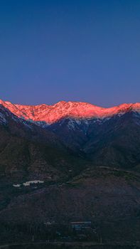 Breathtaking view of snowcapped mountains illuminated by sunrise's warm glow.