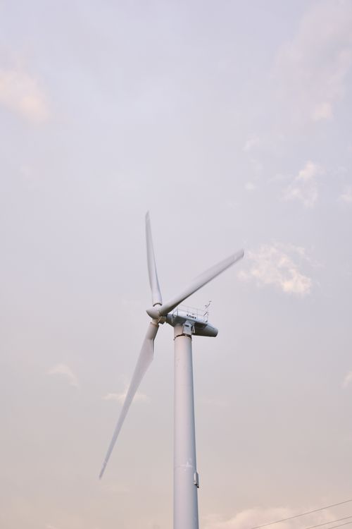 Free A solitary wind turbine standing against a clear sky, symbolizing renewable energy in Thailand. Stock Photo