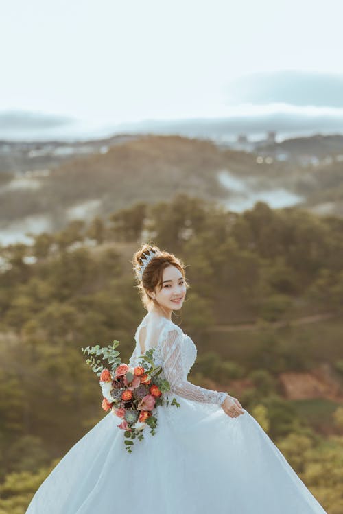Woman in Wedding Dress Holding Bouquet of Flowers