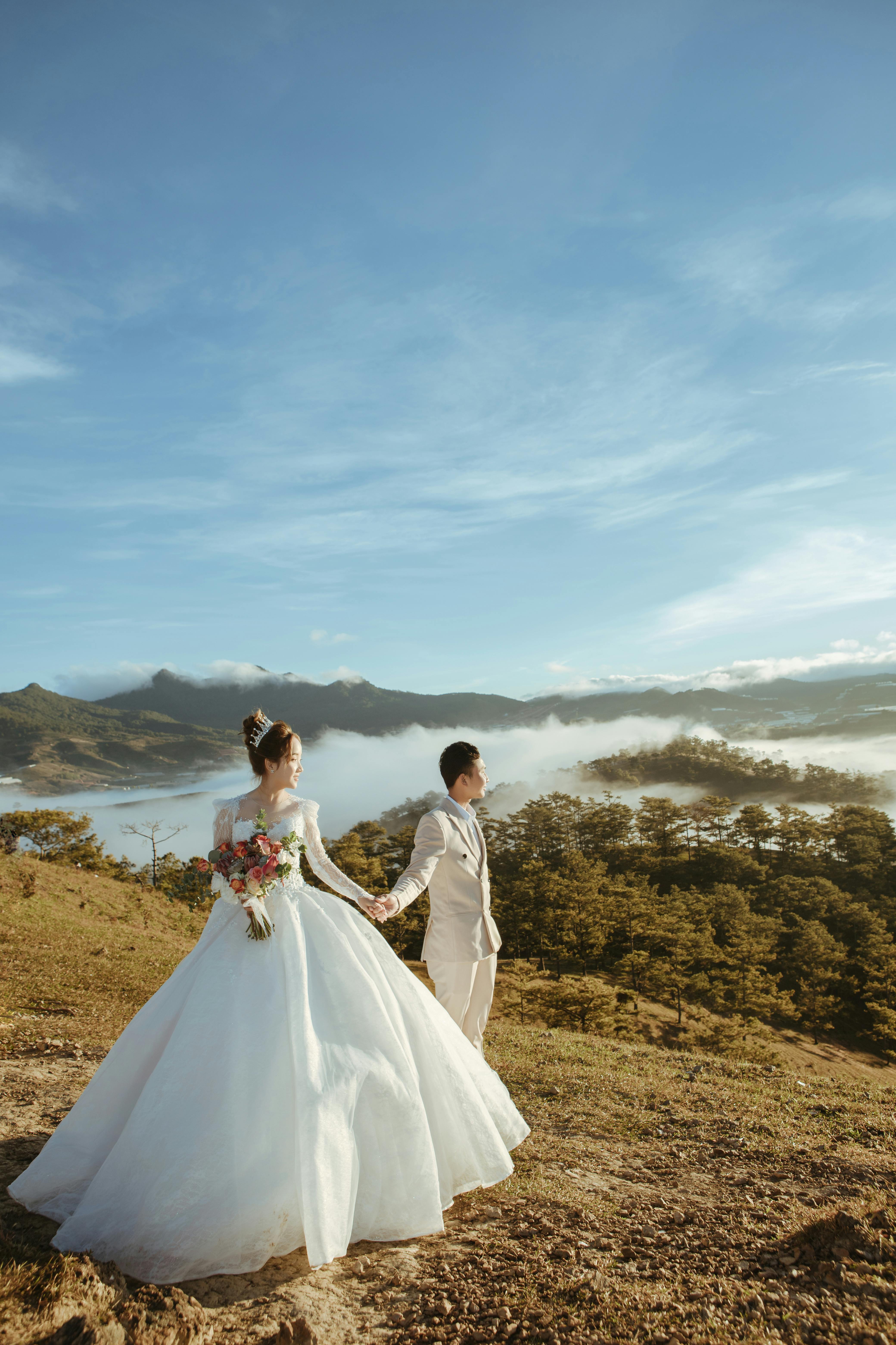 Man and Woman in Wedding Dress Standing on Brown Grass  Free Stock Photo