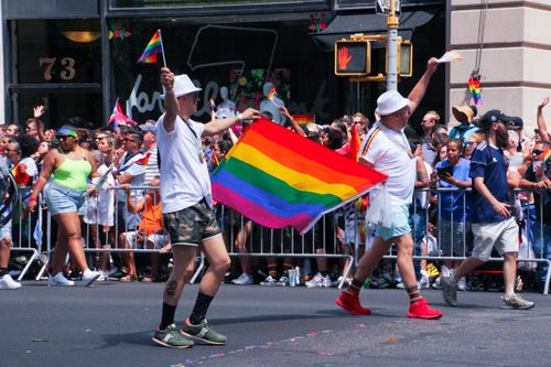 Free Energetic scene from New York City's colorful Pride Parade featuring rainbow flags and diverse participants. Stock Photo