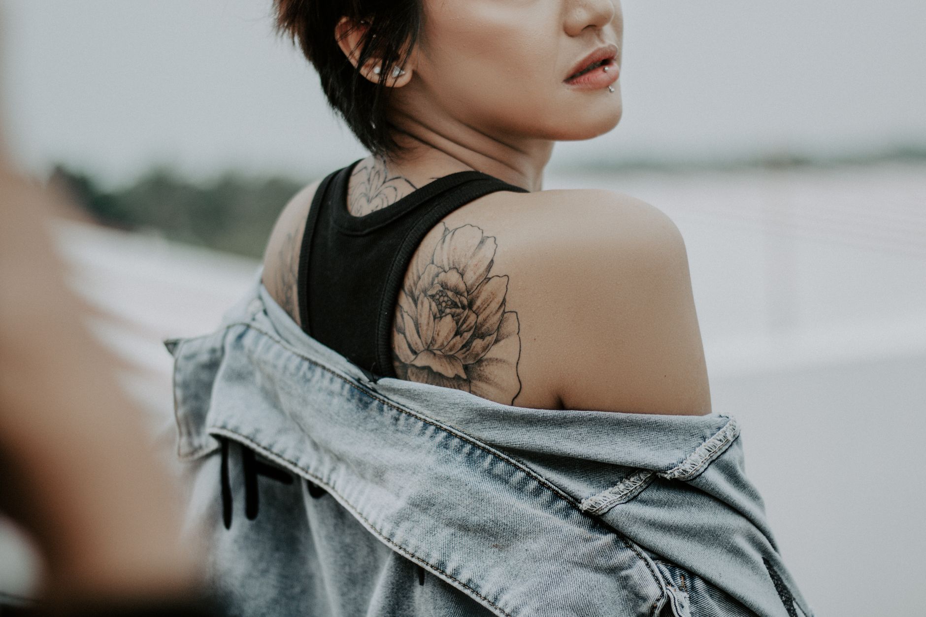 Tatouage floral (pivoine) sur l'épaule d'une femme, style fine line ombré