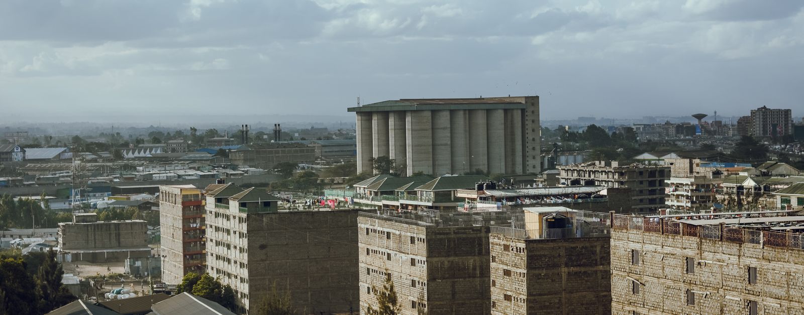 Aerial view of an urban cityscape featuring high-rise buildings and an industrial area under a cloudy sky.