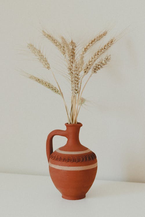 Clay vase with bunch of wheat