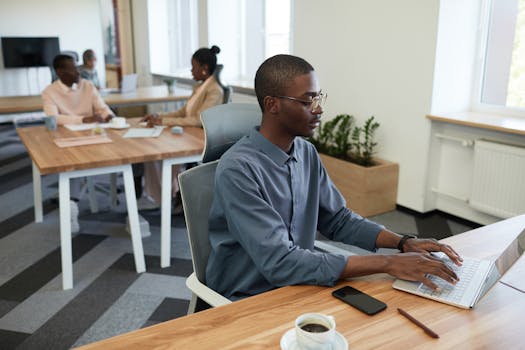 Adult man working on a laptop in a modern office environment, focused and productive.
