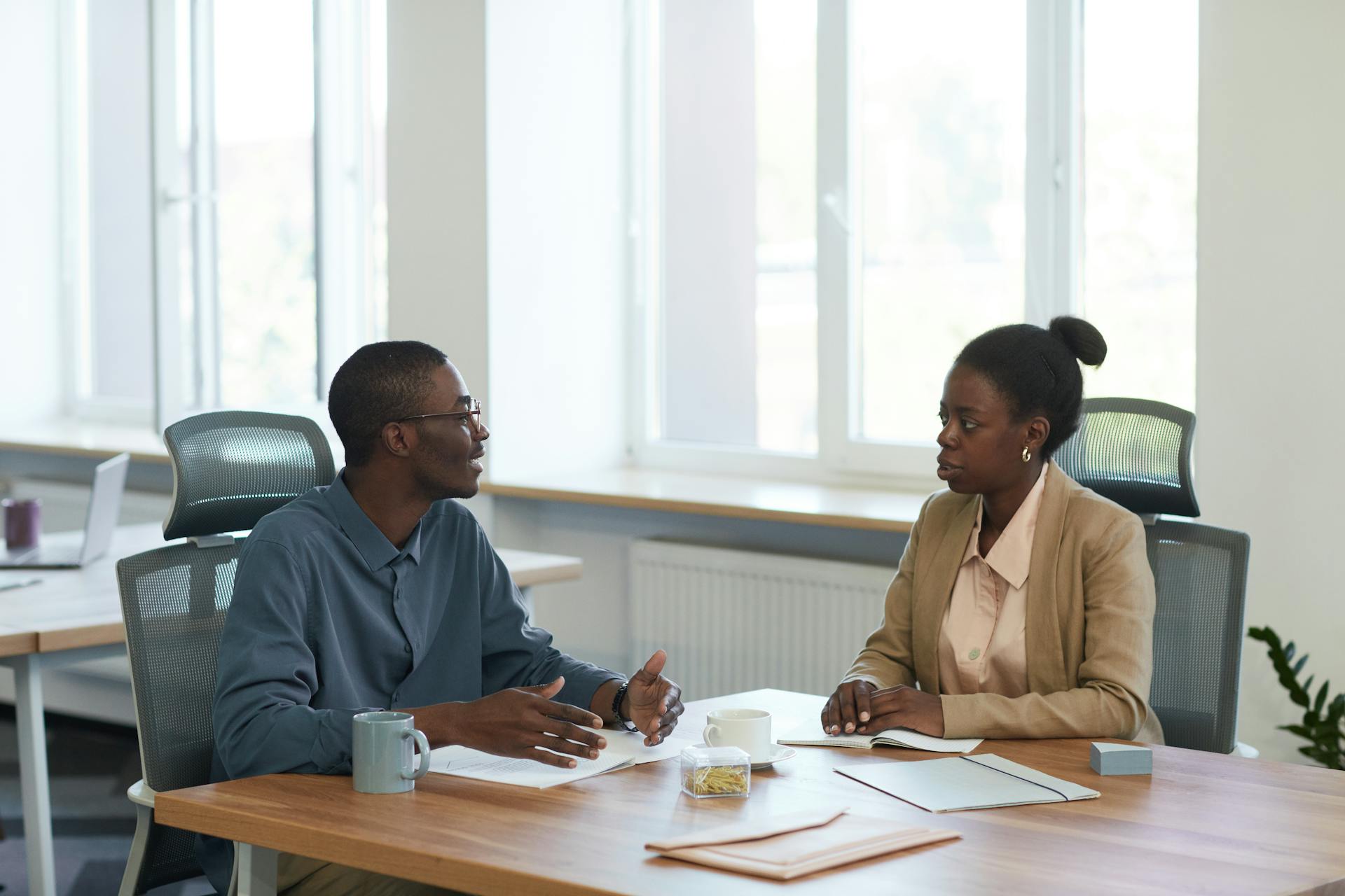 Two colleagues having a business conversation in a modern office setting.