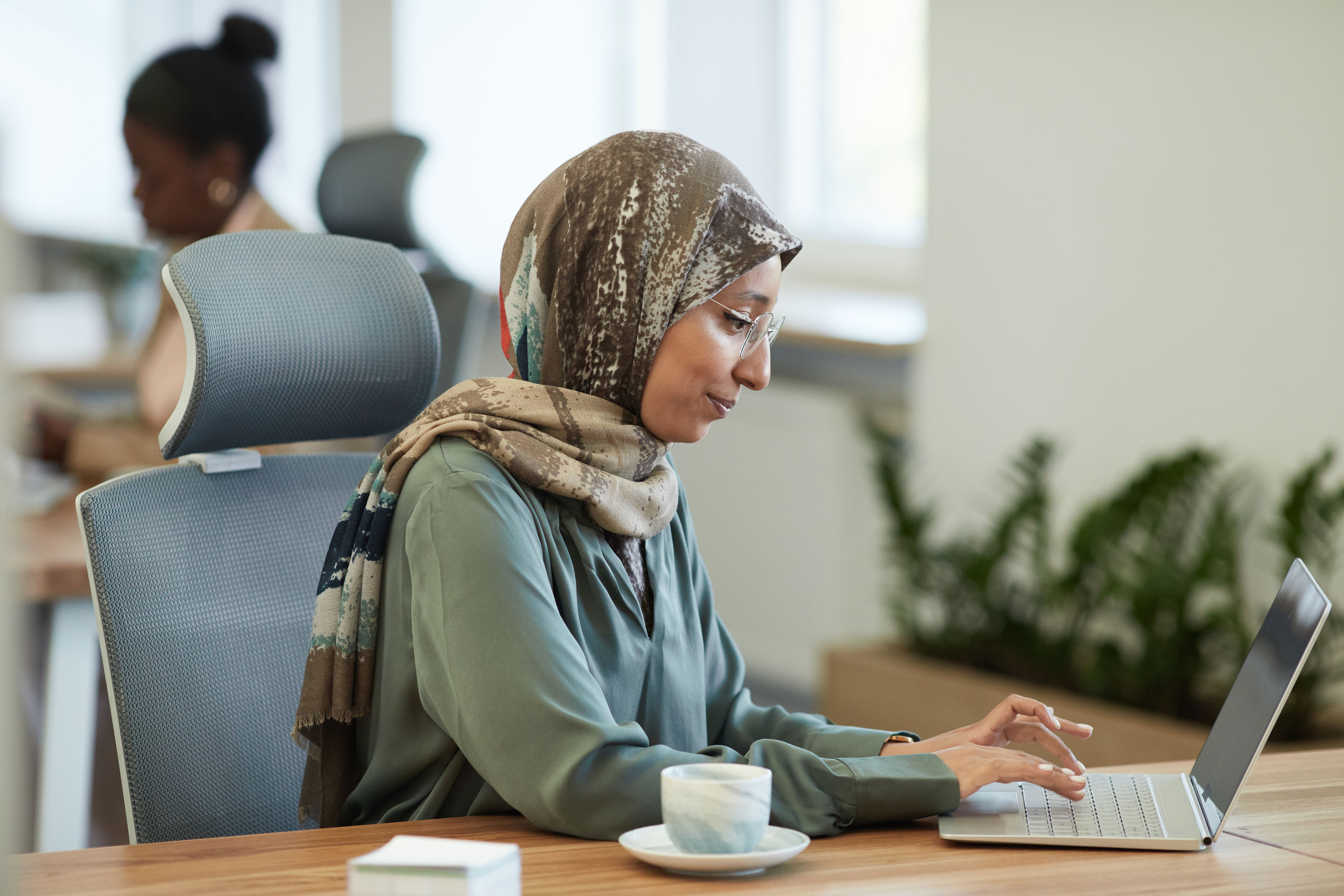 A Woman Wearing Hijab Sitting on a Chair while Busy Working on Her ...