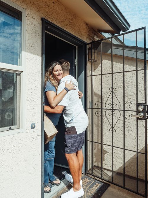 Free A happy moment capturing a man and woman embracing at a home's entrance, symbolizing togetherness. Stock Photo