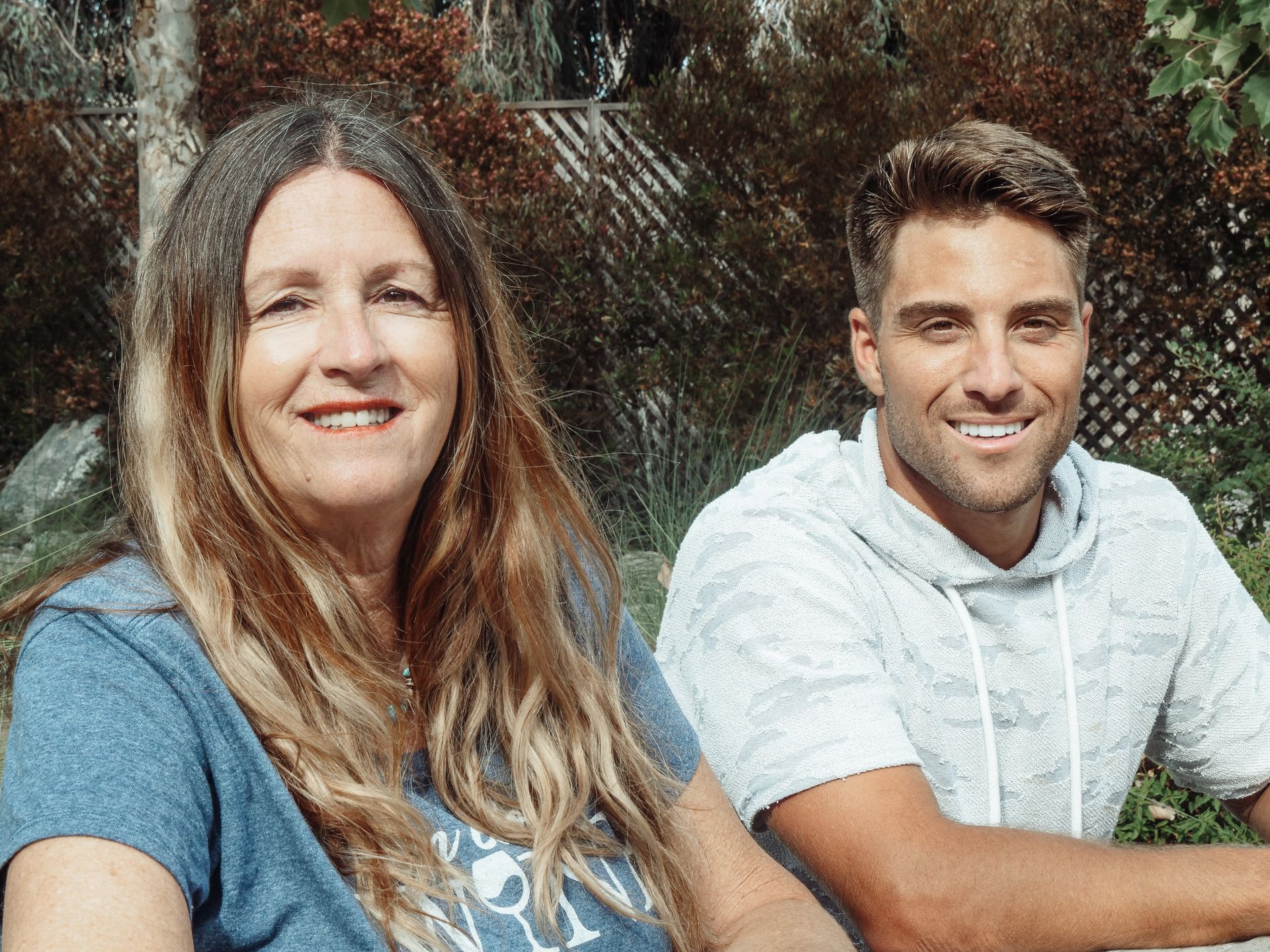 Mother and son enjoying a sunny day outdoors, sitting together and smiling.