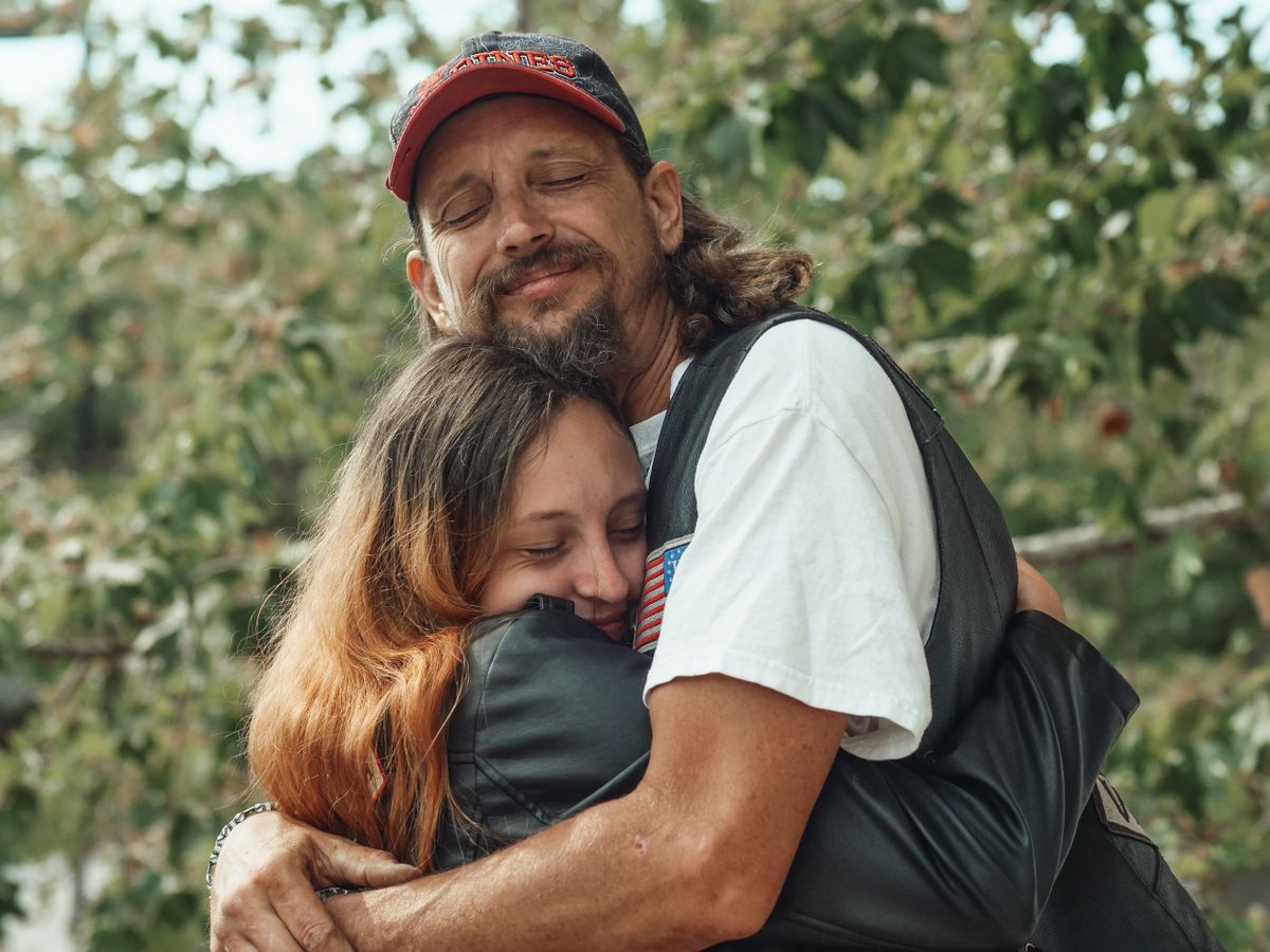 Padre abrazando a su hija al aire libre