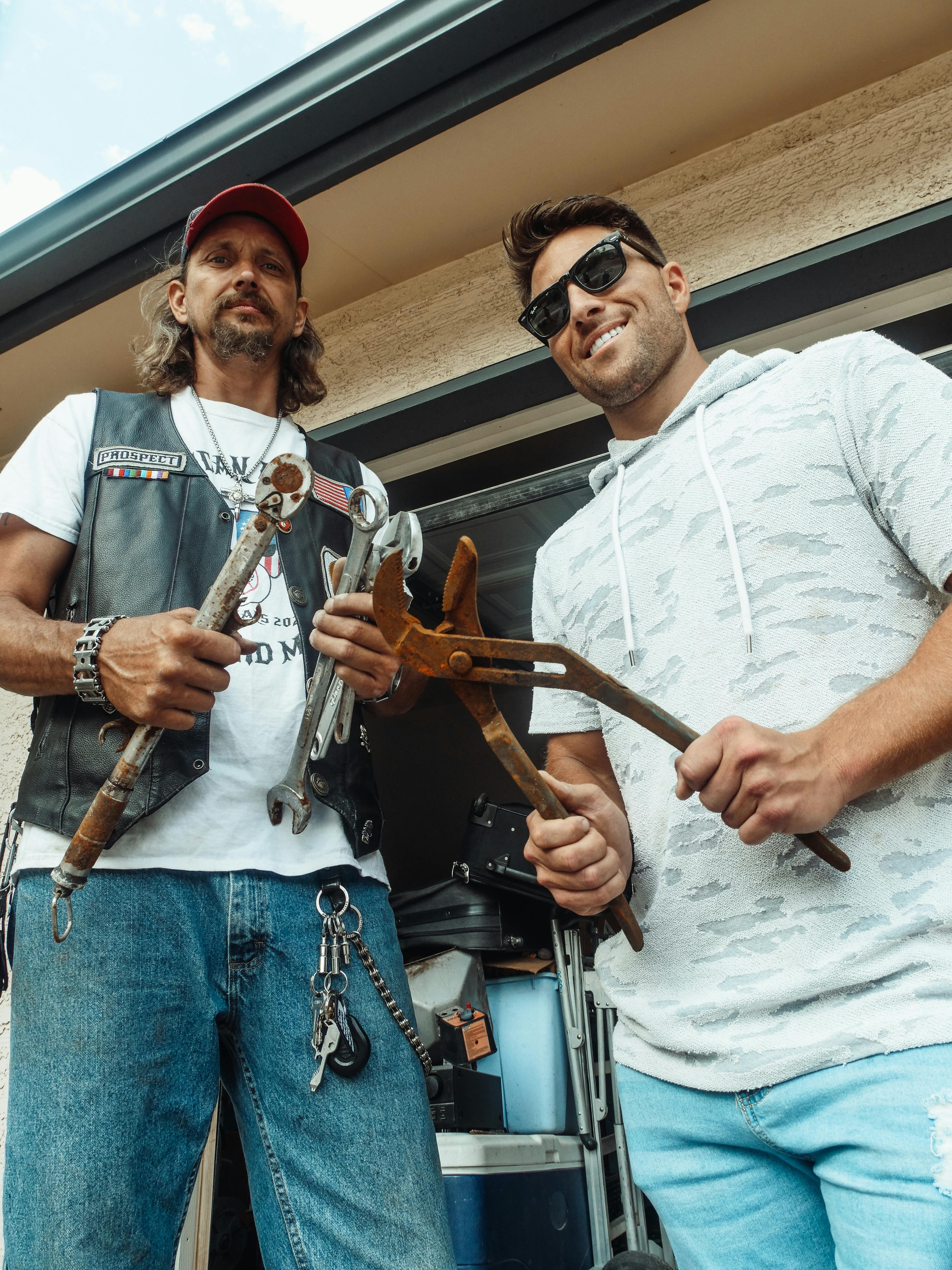 man in white crew neck t shirt holding brown wooden hand tool