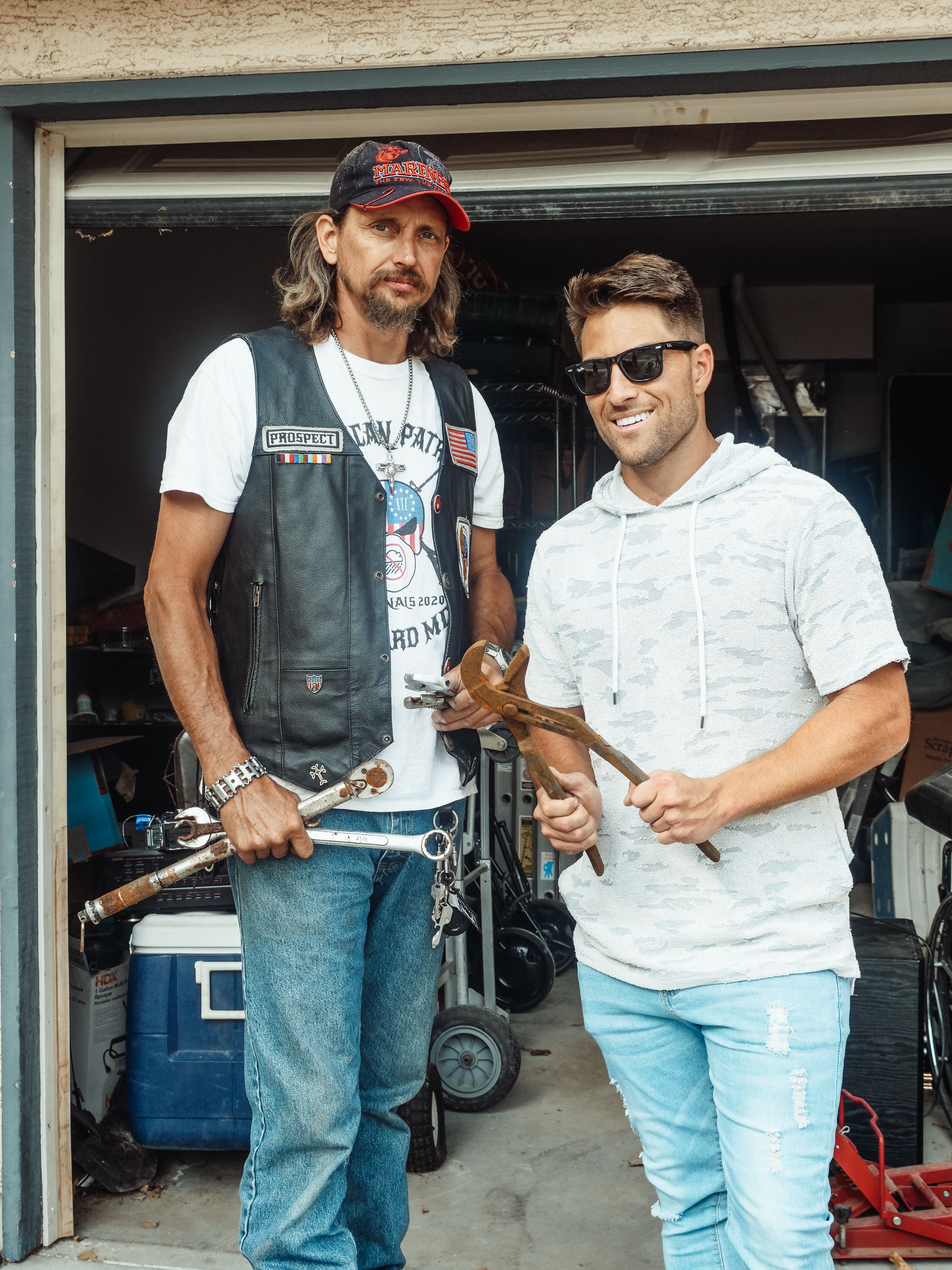 Two men in a garage holding hand tools, embodying the mechanic lifestyle.