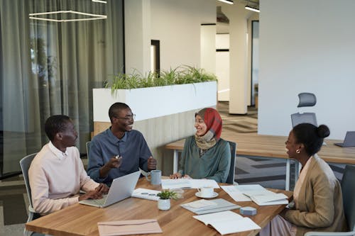 A Group of People Having Conversation while Sitting Near the Wooden Table