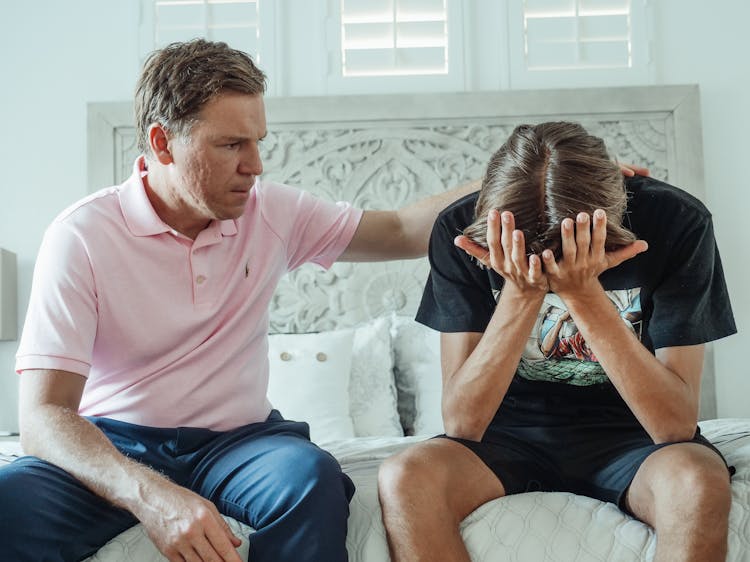 Man In A Pink Shirt Sitting Beside A Teenager Crying