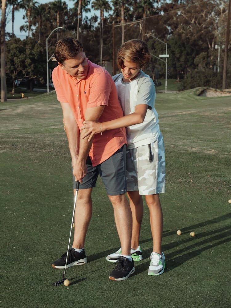 Boy Teaching A Man In Playing Golf