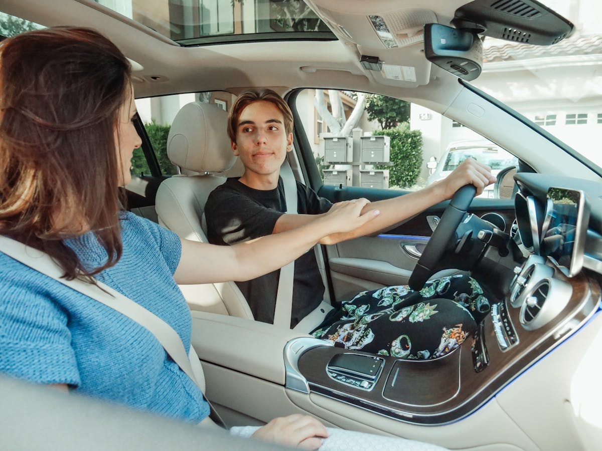 A parent supporting a young learner driver inside a car.