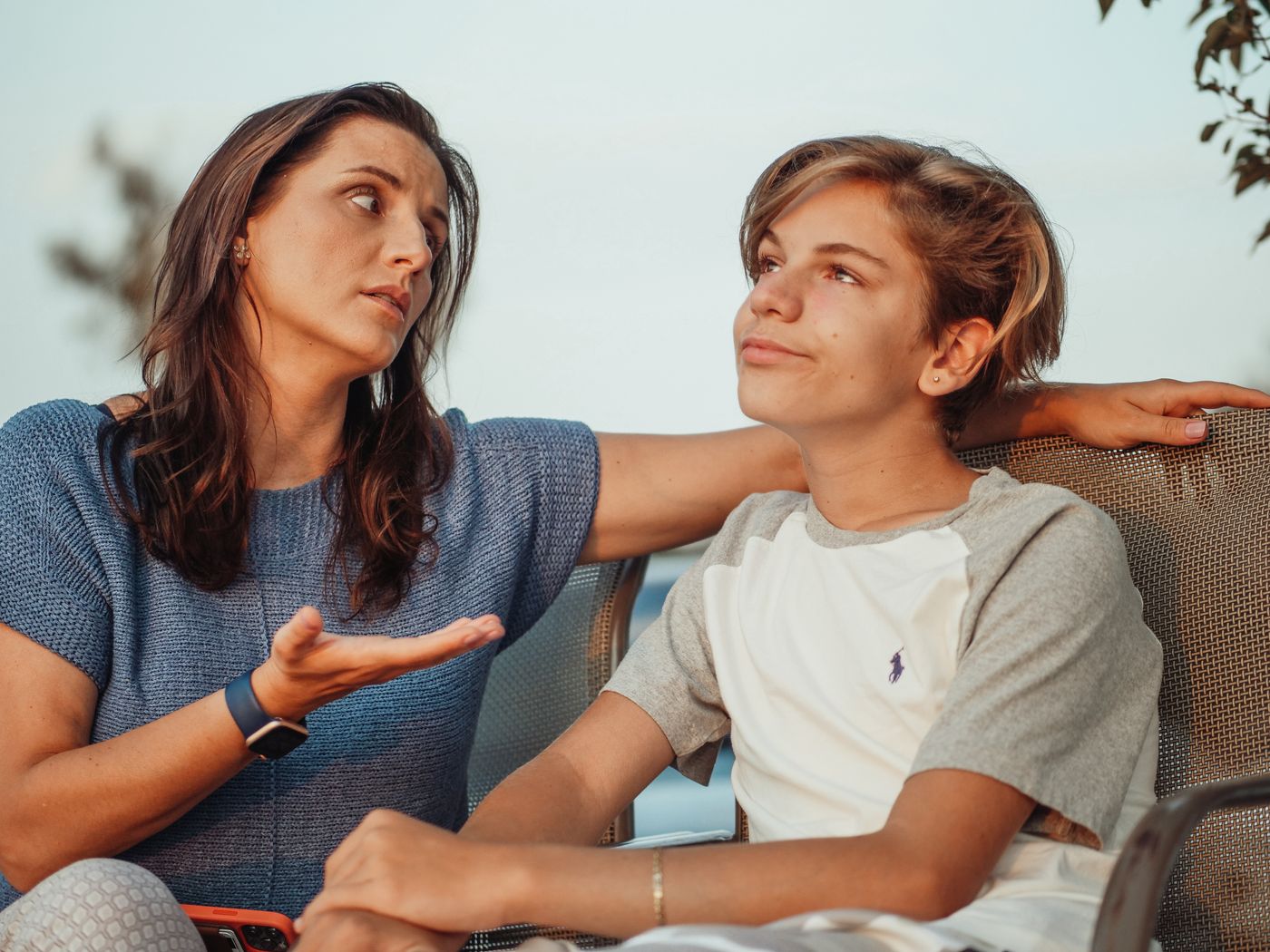 A mother and her teenage son having a warm, open conversation together outdoors.