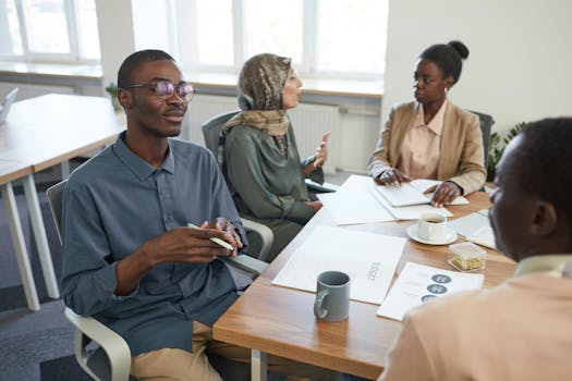 A diverse team engaged in a discussion around a conference table in a modern office setting.