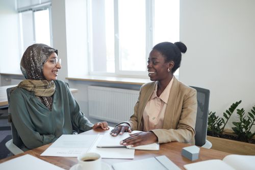 Free Two diverse women in a business meeting, discussing documents in an office setting. Stock Photo