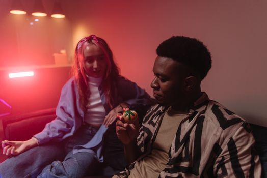 Two friends sitting indoors enjoying cannabis-infused cupcakes with a warm and playful vibe.