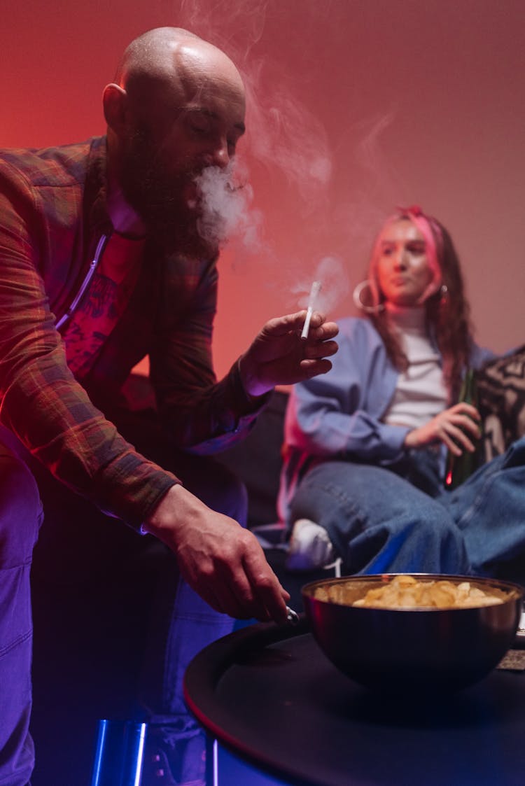 A Man Smoking Cigarette While Eating Chips