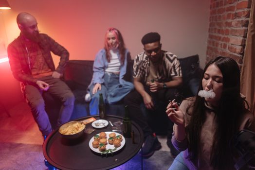 A group of friends enjoying snacks and smoking indoors, capturing a relaxed atmosphere.