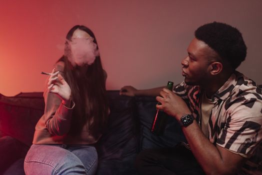 A relaxed indoor scene of friends enjoying drinks and smoking, creating a laid-back atmosphere.