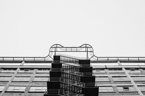 Free Monochrome view of a high-rise building with metal railings and repetitive staircases. Stock Photo