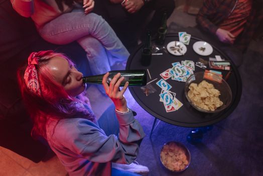 Overhead view of people enjoying drinks and snacks at a party with playing cards.
