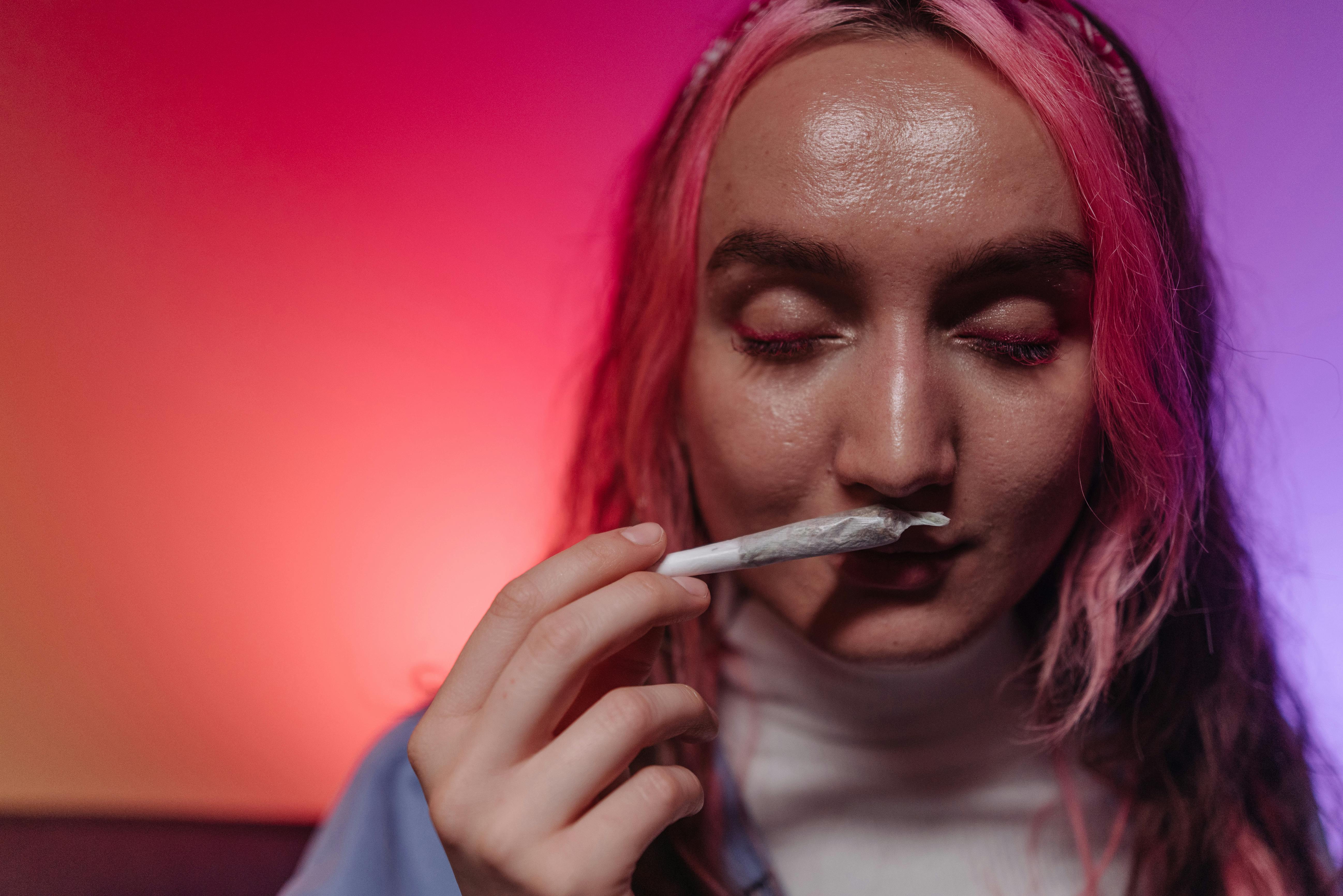 a woman smelling the rolled joint she is holding