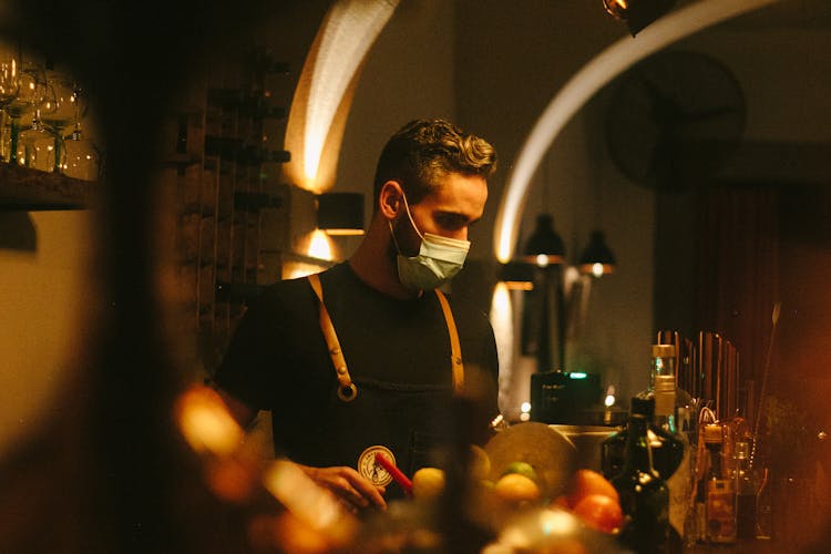 A Bartender Wearing A Face Mask And An Apron