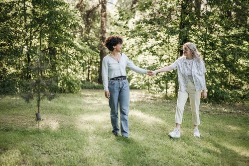 Free A lesbian couple holding hands and enjoying a walk in a sunlit green park. Stock Photo