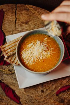 Warm pumpkin soup topped with cheese shavings, paired with toasted bread for a cozy fall meal.