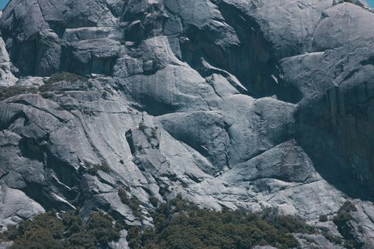 Detailed view of a rocky mountain surface with scattered vegetation below.