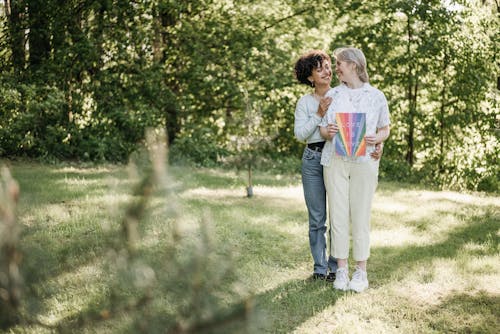 Women Standing on Green Field Near Green Trees while Looking at Each Other