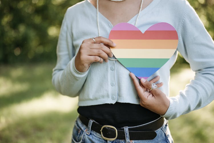 A Person Holding A Heart Shape Cut-out Near Chest