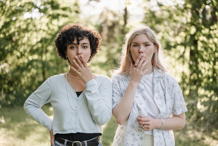 Two Young Women Posing While Smoking Cigarettes