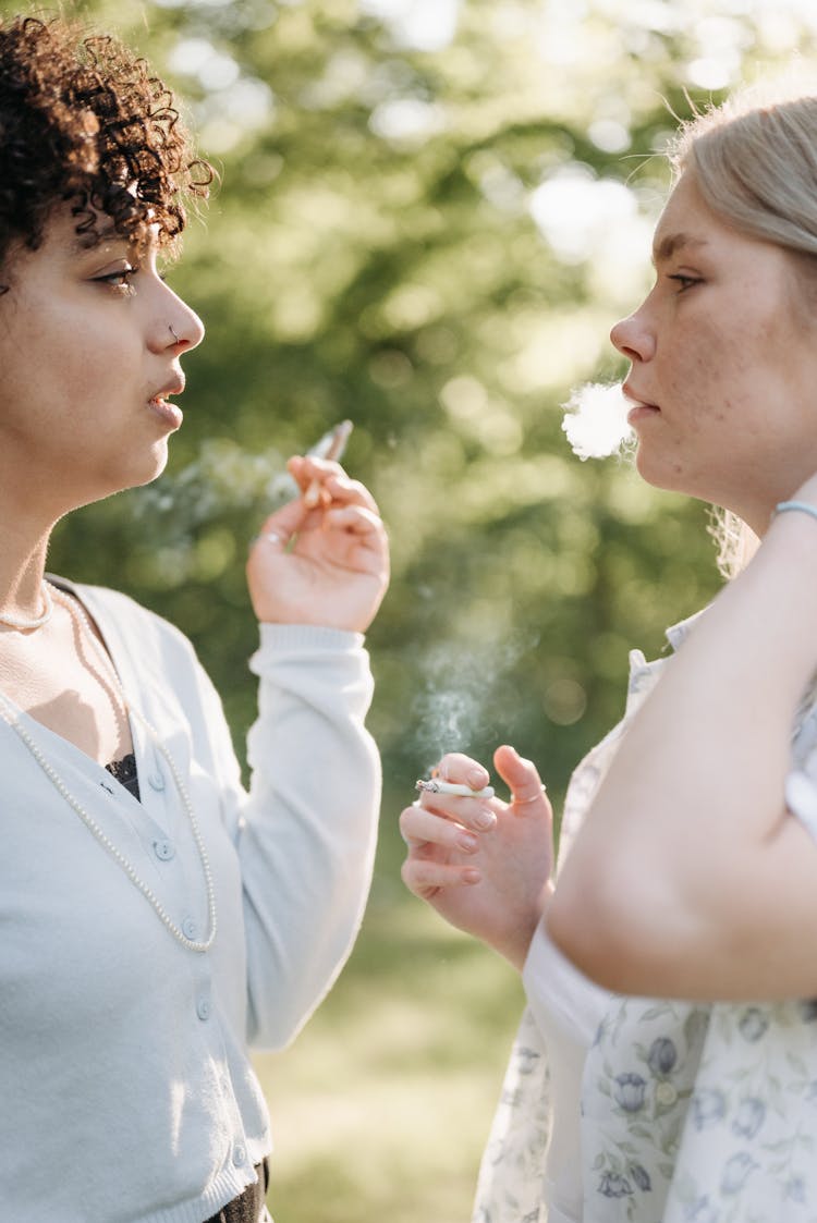 Two Women Looking At Each Other While Smoking Cigarettes