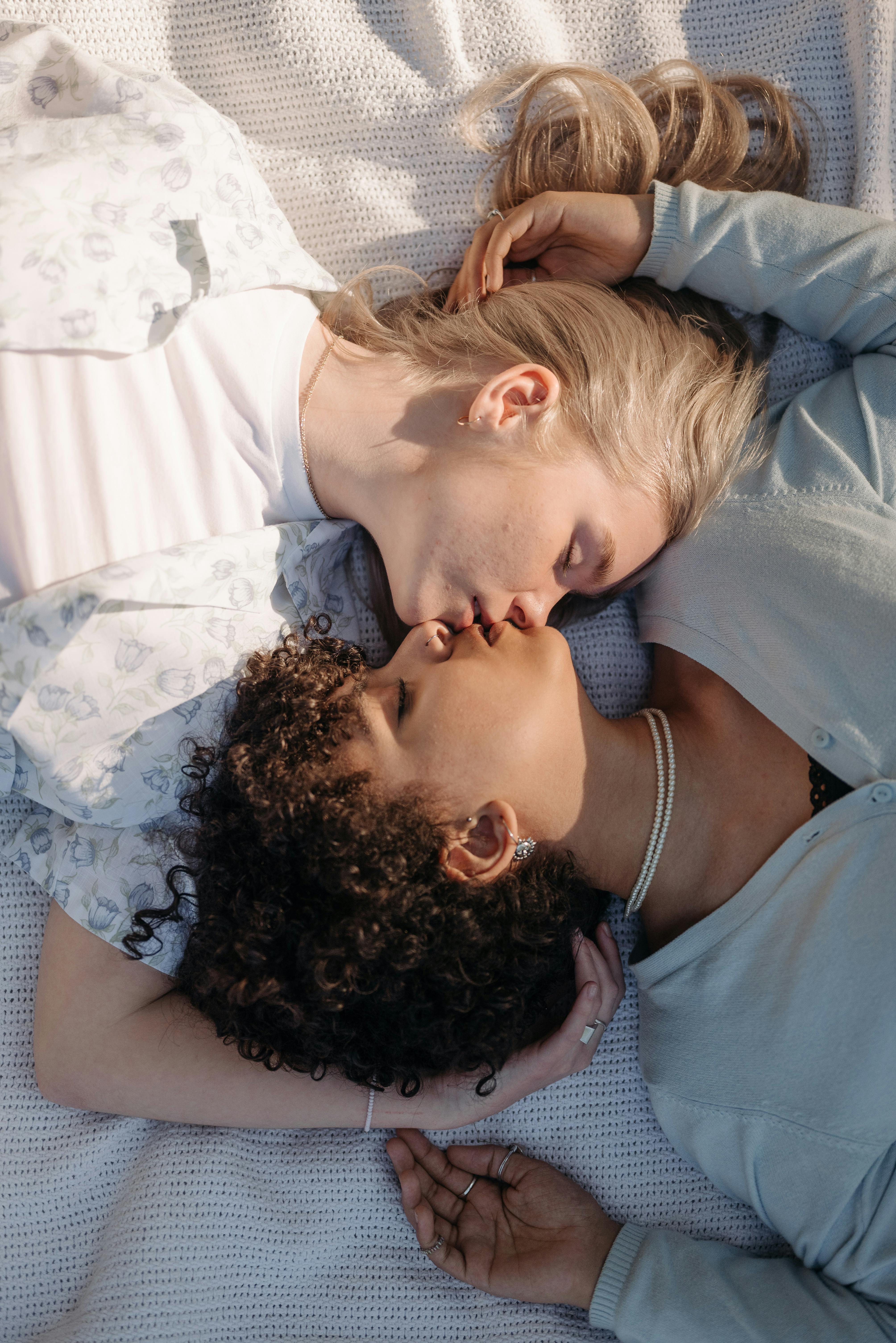 Tender moment of a same-sex couple sharing an intimate kiss while lying down.