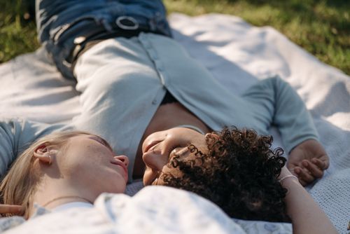 Free A loving couple lying on a blanket outdoors, sharing an intimate and affectionate moment. Stock Photo