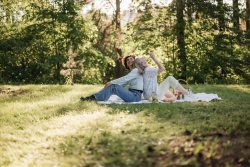 Free Happy couple enjoying a summer picnic in a sunny park, surrounded by lush greenery. Stock Photo