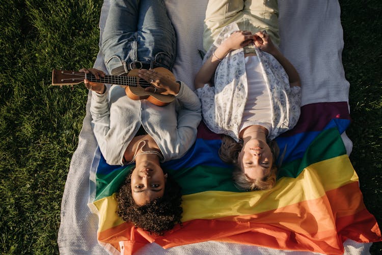 Two Women Lying Down On The Rainbow Flag