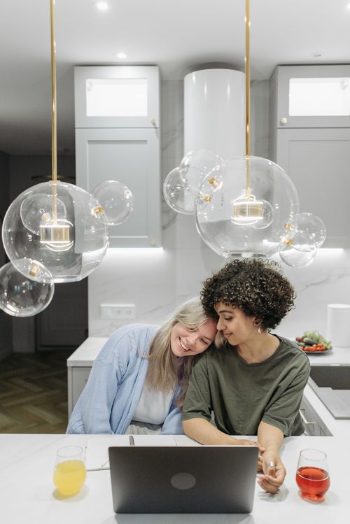 Free Happy couple sharing a moment together in a modern kitchen with a laptop. Stock Photo