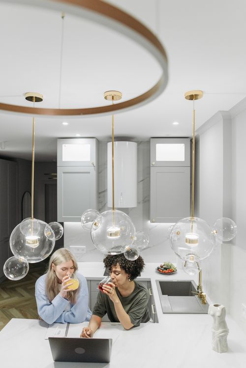 Free A couple enjoying beverages together in their stylish kitchen setup, embracing love and companionship. Stock Photo