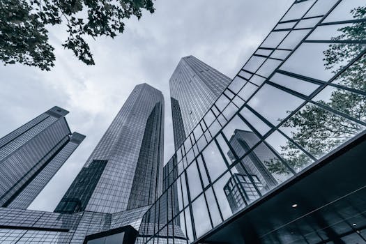 Modern skyscrapers with glass facades reflecting the urban skyline on an overcast day.