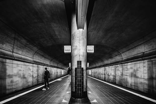 Free Grayscale Photo of a Person Standing on Subway Platform Stock Photo