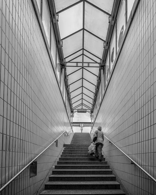 Grayscale Photo of a Woman Walking Up the Stairs