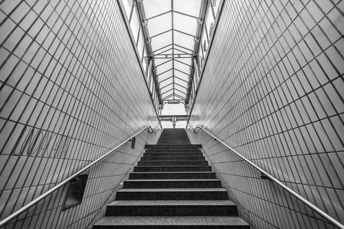 Free Black and white photo of a subway entrance staircase with tiled walls. Stock Photo