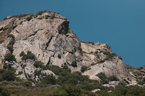 Free Stunning view of a rocky cliff face under a bright blue sky, showcasing natural geological formations. Stock Photo