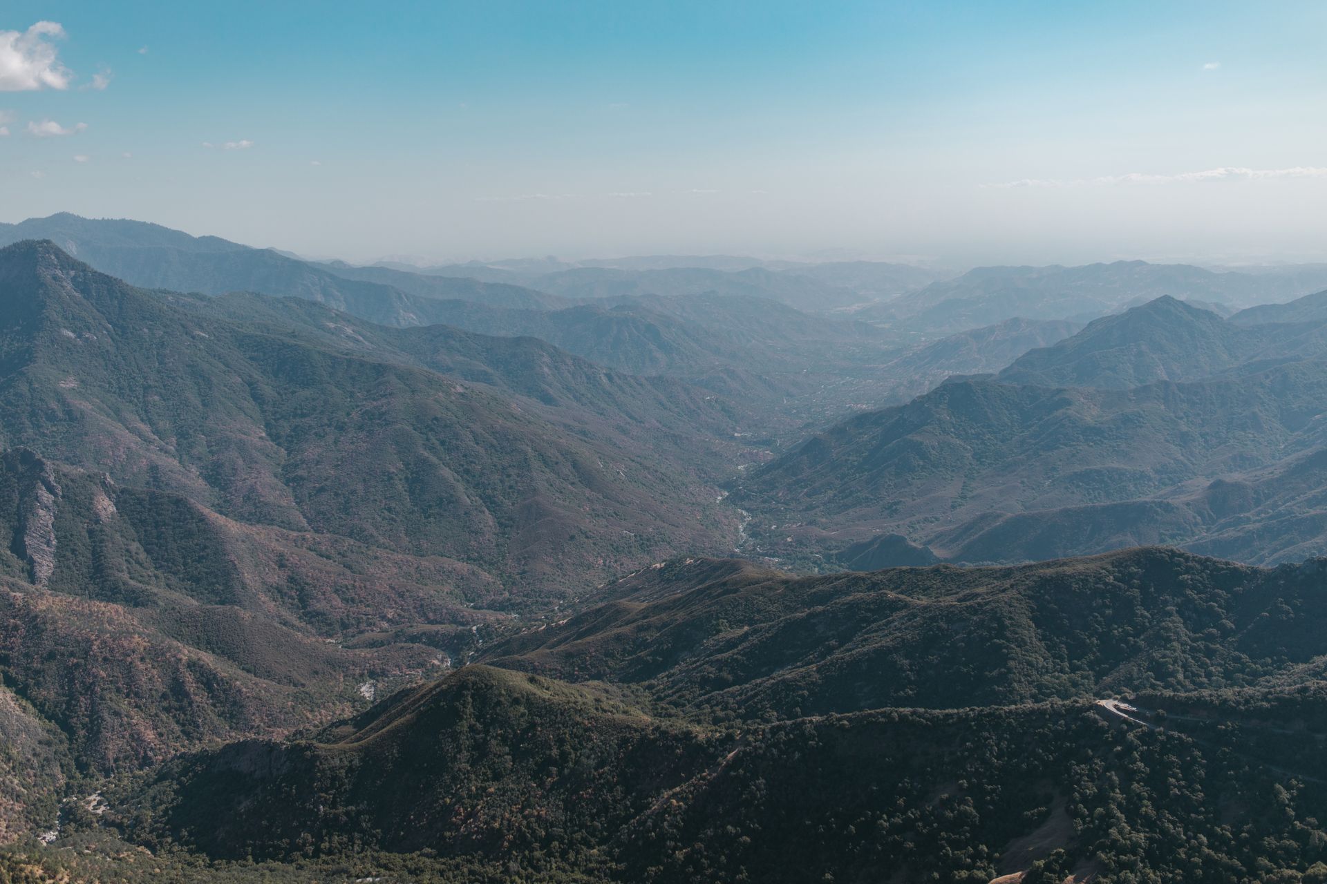 Stunning aerial view of a vast mountain range with misty valleys and scenic landscapes.